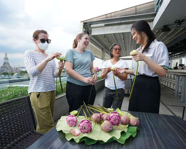 Four grown-ups holding lotus flowers and smiling.